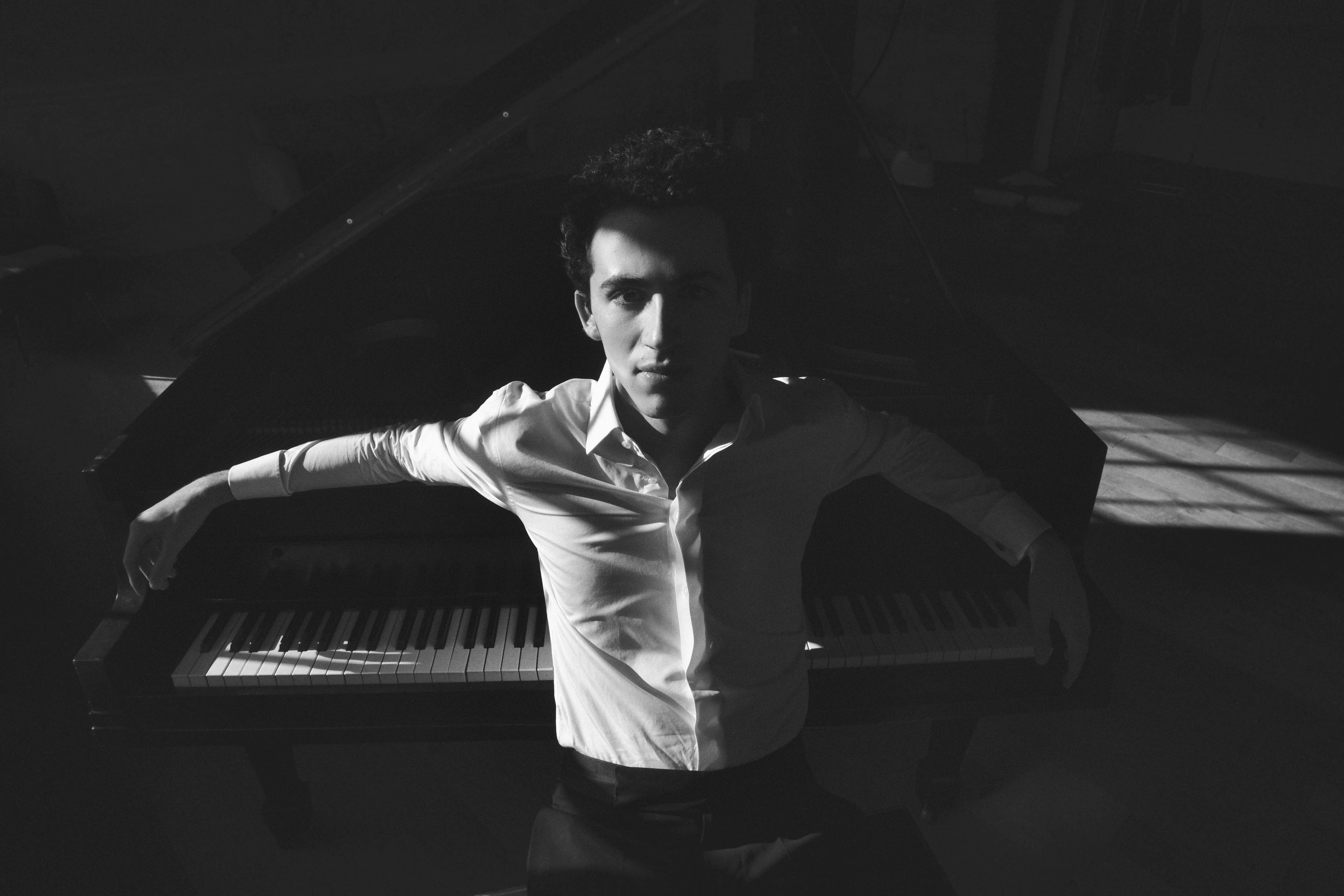 Kiron Atom Tellian, white shirt, leaning back at the grand piano.